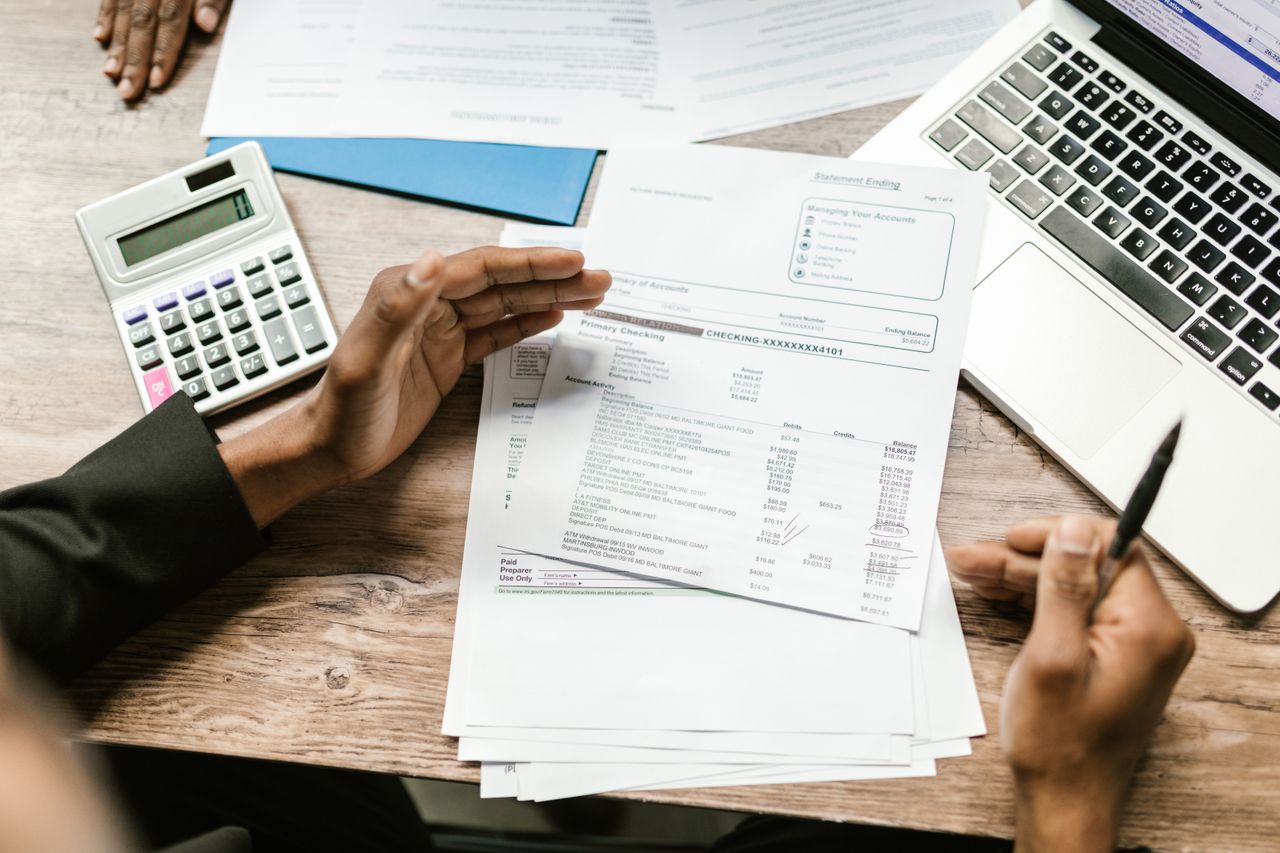 The Art of Drawing Readers In: Your attractive post title goes here Hands holding financial documents with calculator and laptop on office desk, business analysis scene.