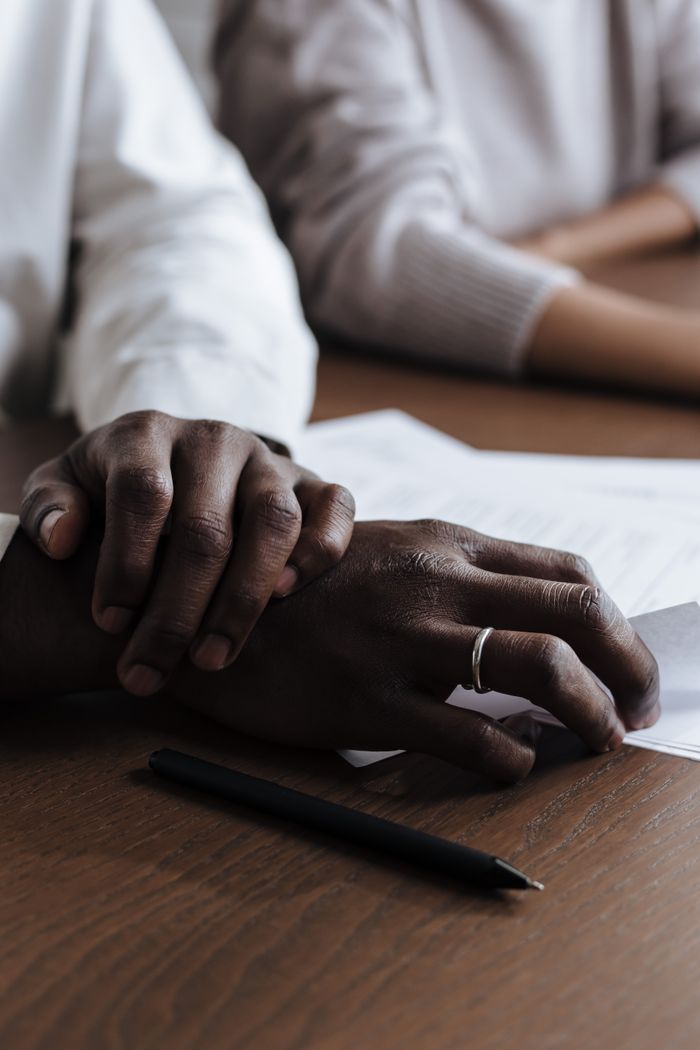 mission-img Close-up of diverse hands resting on documents at a table, showing partnership and collaboration.
